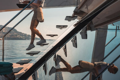 A stewardess carries drinks down the reflected stairs of superyacht STRADIVARIUS aft deck